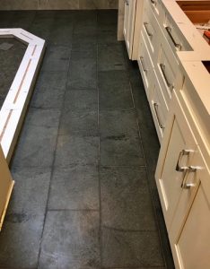 Soapstone tile completes this bathroom with a dark contrast to white cabinets and beautiful natural veining.